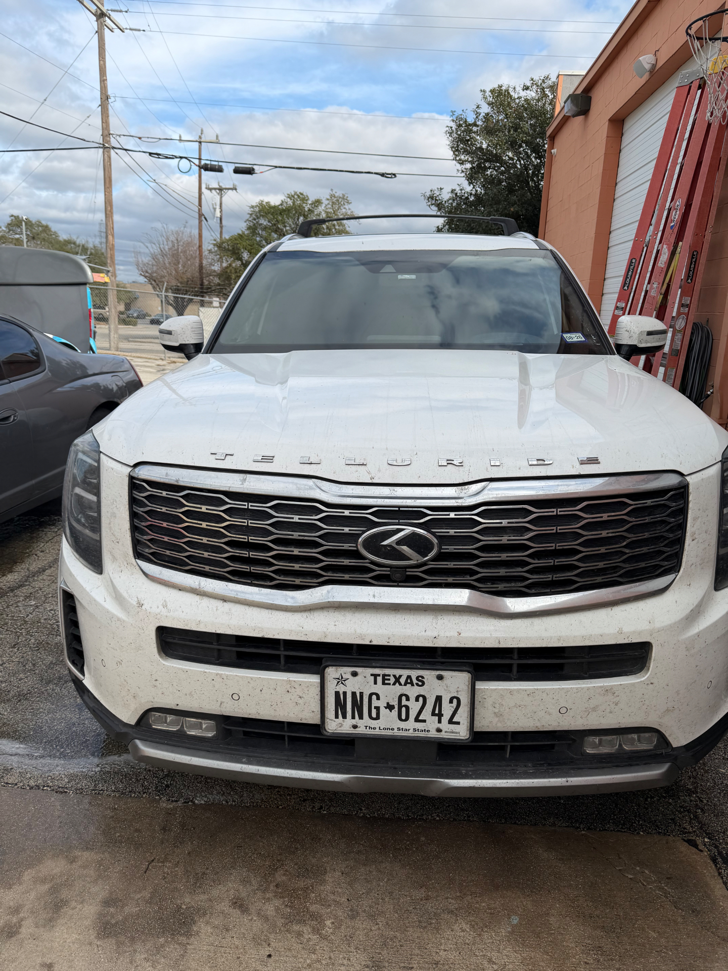 White Kia Telluride covered in road grime before detailing